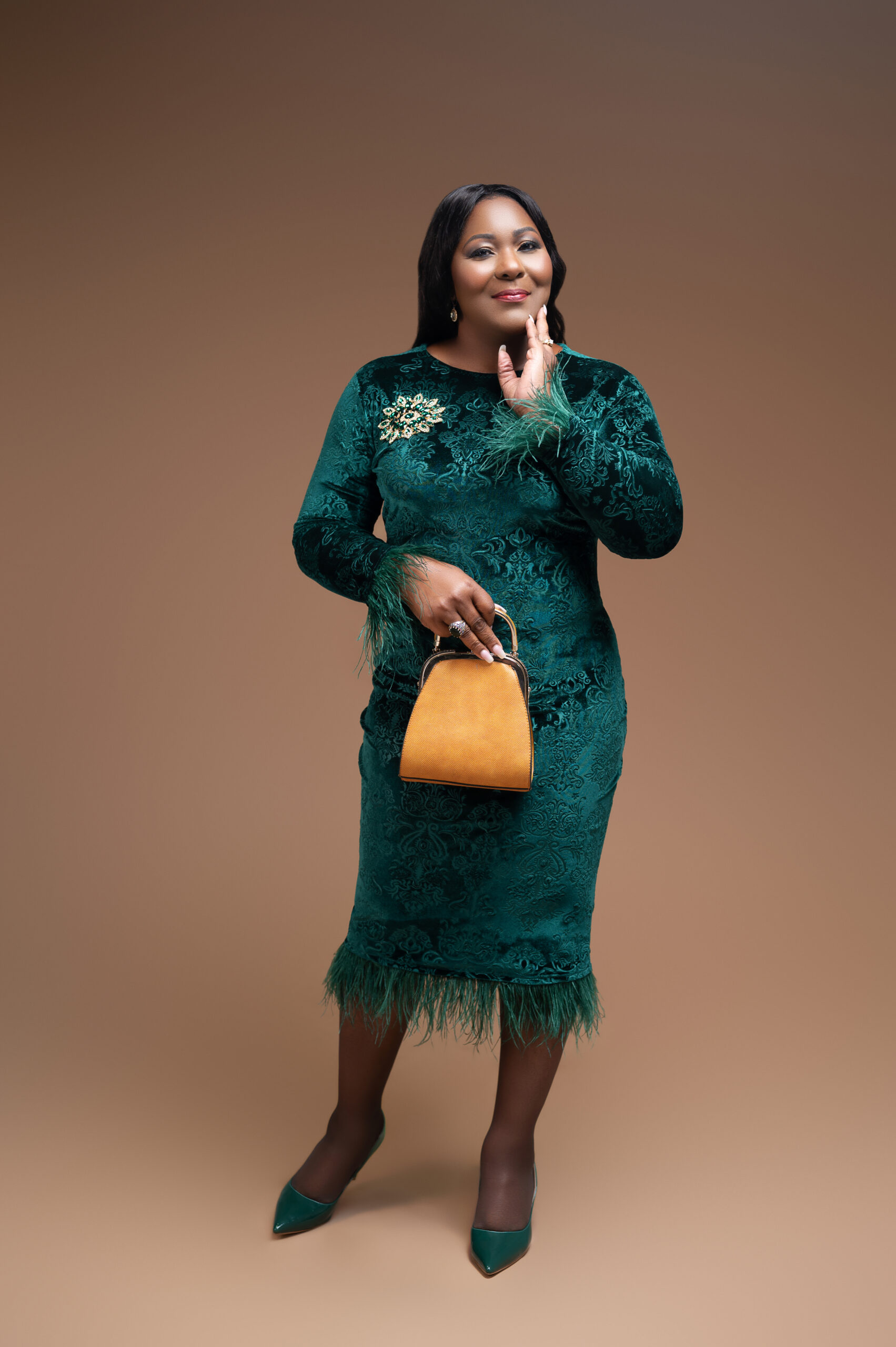 A portrait photo of Dr. B with her hand to face in  green dress